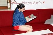 Lucy wearing a sexy red shiny nylon shorts and a blue shiny nylon rain jacket during reading a bit on the sofa (Pics)