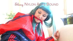 Mara tied and gagged on a sofa wearing a sexy blue shiny nylon shorts and a red/blue Rain jacket (Pics)