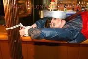 An archive girl tied and gagged on a bar wearing shiny nylon rainwear (Pics)