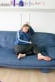 Katharina posing on a sofa wearing a blue/black shiny nylon rainwear (Pics)