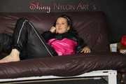 Watching Mara preparing bed and lolling and posing wearing a sexy shiny rain jacket and a rain pants (Pics)