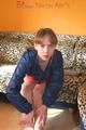 Leonie posing on a leopard sofa wearing a red shiny nylon shorts and an oldschool red/darkblue rain jacket (Pics)