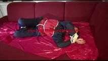 Lucy tied and gagged with ropes and a cloth gag on a sofa wearing a blue/red rainwear combination (Video)