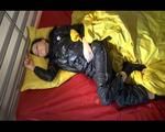 Lucy lolling in bed wearing a sexy black rainwear combination (Video)