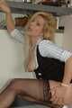 Pierced mature blonde Nina posing in a tight businessdress and stockings in front of the kitchen