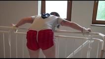 Jill tied and gagged on a stairrail wearing a sexy shiny red shorts with shadow stripes and a top (Video)