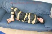 Katharina tied, gagged and hooded with tape on a sofa wearing sexy shiny nylon rainwear (Pics)
