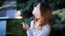 Adorable party girl Irina taking a drag on a Marlboro Red cigarette in the city park