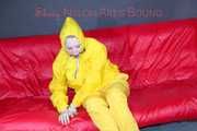 MARA ties, gagges and hoodes herself with cuffs and a ballgag on a sofa wearing sexy yellow rainwear (Pics)