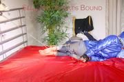 Sonja tied, gagged and hooded on bed with cuffs wearing a sexy grey shiny nylon rain pants and a blue down jacket (Pics)