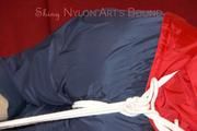 Lucy tied, gagged and hooded with ropes on a sofa wearing a sexy blue/red rainwear combination (Pics)