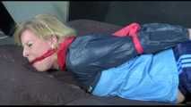 Pia tied and gagged with gymnastic bands and a cloth gag on bed wearing a sexy shiny nylon shorts and an oldschool rain jacket (Video)