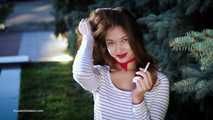 Adorable party girl Irina taking a drag on a Marlboro Red cigarette in the city park