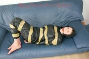 Katharina tied, gagged and hooded with tape on a sofa wearing sexy shiny nylon rainwear (Pics)