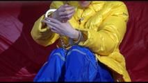 Sonja wearing a blue rain pants and a yellow PAMY down jacket while bonding herself an the sofa (Video)