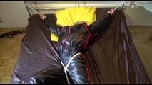 Liz tied and gagged on a bed wearing an oldschool black/red shiny nylon downwear combination (Video)