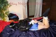 SEXY LUCY wearing a blue shiny nylon shorts and a black shiny rain jacket being tied and gagged with ropes and a clothgag on the bed (Pics)