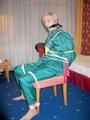 Blonde archive girl tied and gagged in an green shiny nylon rainsuit on a chair (Pics)
