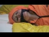Samantha tied and gagged in bed wearing an orange/grey shiny nylon rainwear combination (Video)