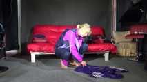 Watching Pia wearing a blue/purple/pink shiny nylon rain suit folding clothes and tidying up the studio (Video)