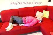 Mara tied and gagged on a red sofa wearing a sexy black rain pants and a shiny pink down jacket (Pics)