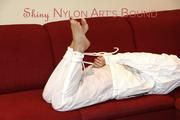 Pia tied and gagged on a sofa wearing a shiny white rain combination (Pics)