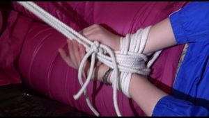 Mara tied, gagged and hooded on a sexy black covered sofa wearing a blue rain jacket and pink rain pants (Video)