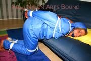 Katharina tied and gagged on a sofa wearing blue shiny downwear (Pics)