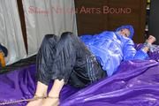 Pia tied, gagged and hooded with cuffs and chains on a bed wearing a sexy black rain pants and a blue down jacket (Pics)