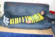 Katharina tied and gagged with tape on a sofa wearing shiny rainwear (Pics)
