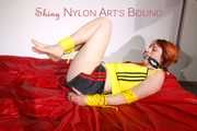 Sonja tied and gagged on a bed wearing sexy black shiny nylon shorts and a yellow top (Pics)
