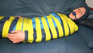 Katharina tied and gagged with tape on a sofa wearing shiny rainwear (Pics)