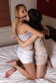 Gagged with a double ballgag, barefoot Dolly and Jessica, tied kneeling face to face, wiggles on the bed