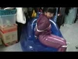 Video with Jill tied and gagged in a shiny purple semi transparent PVC suit