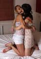 Gagged with a double ballgag, barefoot Dolly and Jessica, tied kneeling face to face, wiggles on the bed