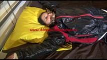 Liz tied and gagged on a bed wearing an oldschool black/red shiny nylon downwear combination (Video)