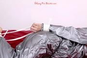 Pia tied and gagged in a shiny silver sauna suit bare feet on a bed (Pics)