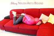 Mara tied and gagged on a red sofa wearing a sexy black rain pants and a shiny pink down jacket (Pics)