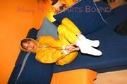 Archive girl tied and gagged on sofa wearing a shiny yellow rainwear (Pics)