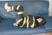 Katharina tied, gagged and hooded with tape on a sofa wearing sexy shiny nylon rainwear (Pics)