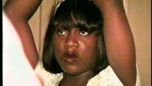 BLACK BANK TELLER IS MOUTH STUFFED, TAPE GAGGED, & TIED STANDING WITH HER HANDS TIED OVER HER HEAD & TO A COAT HANGER ON THE DOOR (D49-13)