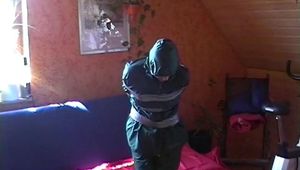 Beautiful archive girl in a green shiny nylon rainsuit tied and gagged with tape on a sofa trying to free herself(Video)