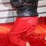 Sonja tied and gagged with a pillory on bed wearing a sexy red rain pants and a black down jacket (Pics)