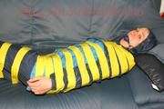 Katharina tied and gagged with tape on a sofa wearing shiny rainwear (Pics)