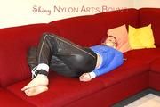 Mara tied and gagged on a sofa wearing a shiny black rain pants and a sexy lightblue down jacket (Video) 