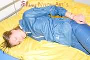 Alina wearing a sexy shiny rainwear suit in blue lolling on bed cuffed (Pics)