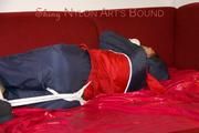 Lucy tied, gagged and hooded with ropes on a sofa wearing a sexy blue/red rainwear combination (Pics)