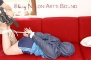 Jill tied, gagged and hooded with ropes on as sofa wearing a blue shiny nylon shorts and a blue oldschool rain jacket (Pics) 